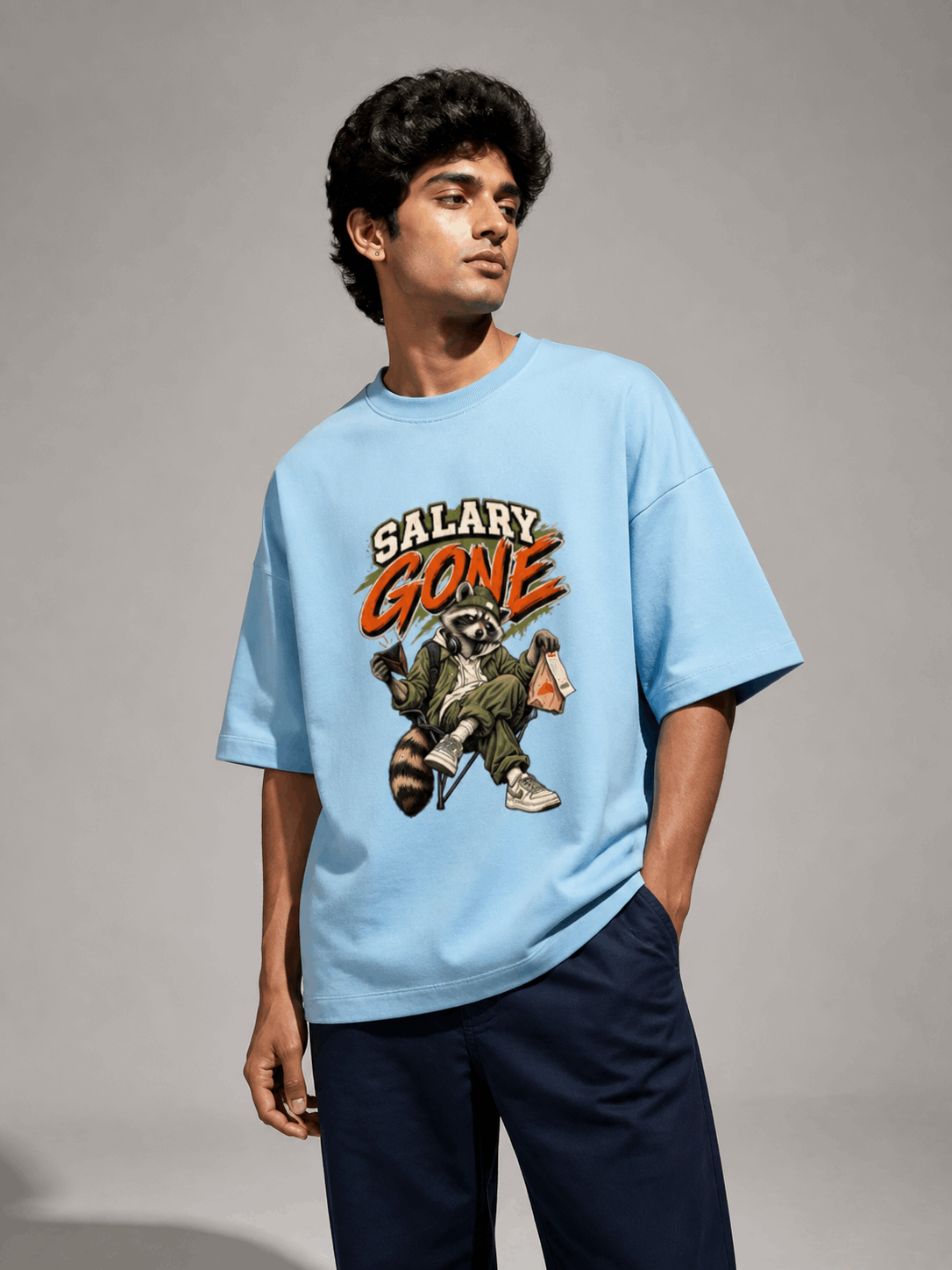 Salary Gone Raccoon baby blue oversized T-shirt on Indian male model, three-quarter studio view